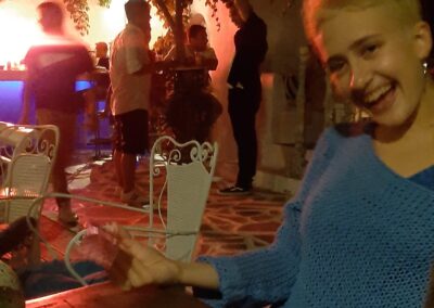 people sitting at a table with plates and glasses in front of them at night time