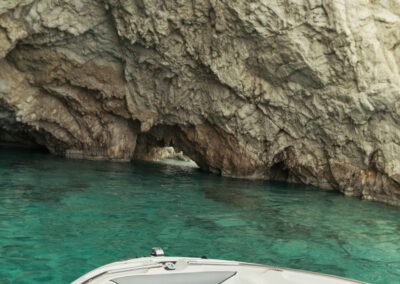 The bow of the boat is entering a Keri cave with turquoise waters underneath.