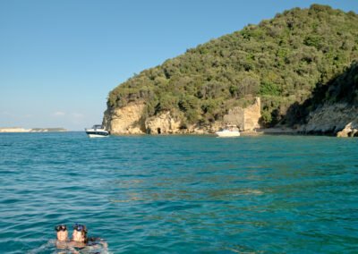 Two women swimming together with masks and snorkels in the sun by Marathonisi "Turtle island" in Zakynthos.