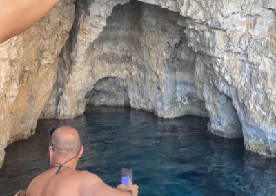 The back of a man on the bow of a speedboat inside the Keri caves.