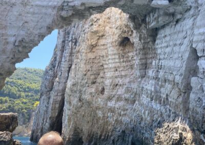 A tourist taking a picture of the famous rock arch over bright turquoise water in Zakynthos Keri caves.