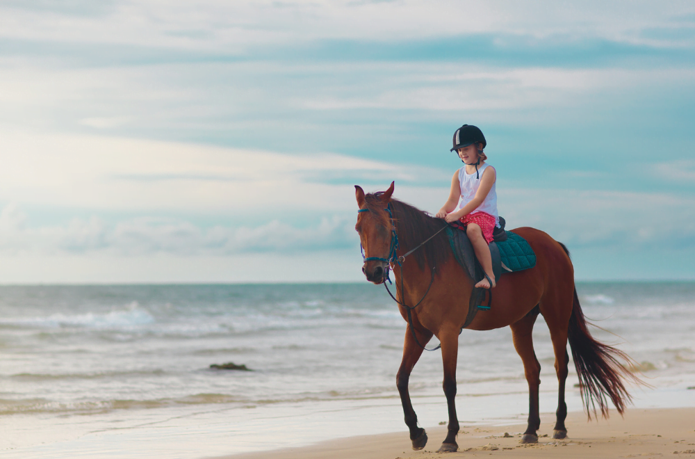A little girl riding a horse on the beachside in Zakynthos Island