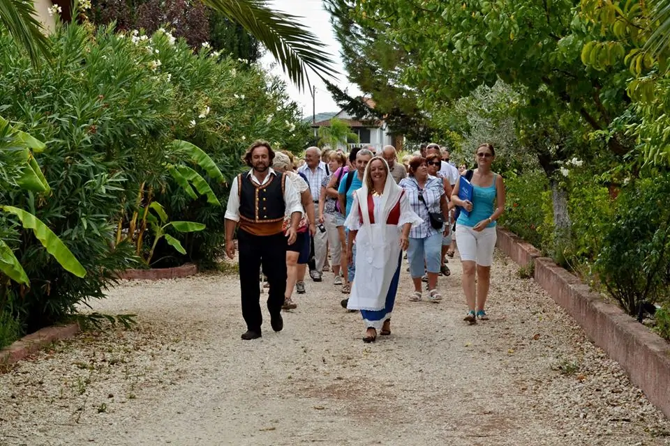 Guides in Therianos Organic Farm wearing traditional costumes, walking group of people inside the farm