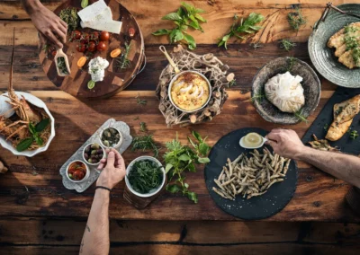 Hands on table with Greek local cuisine, herbs, tzatziki and more